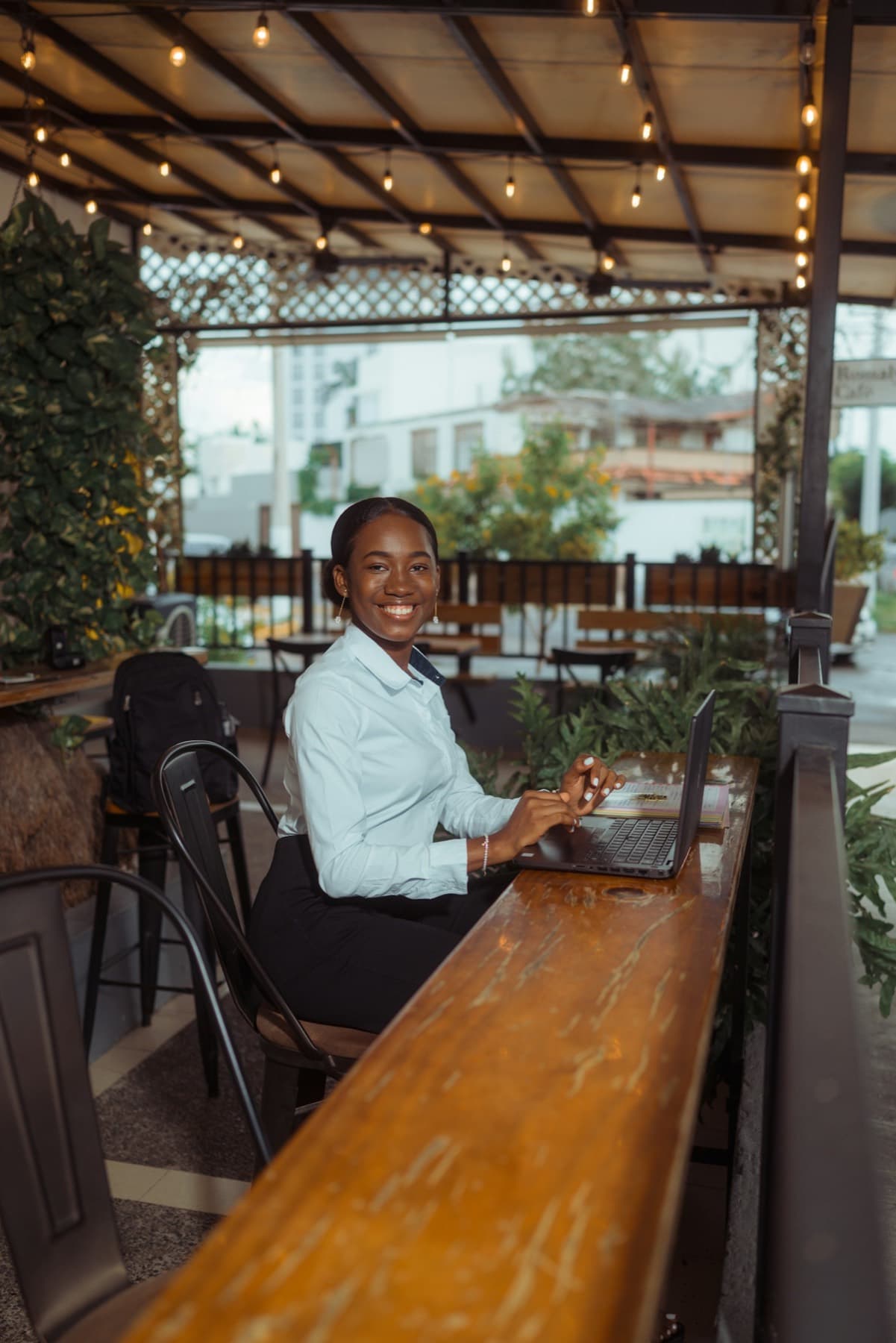 Entrepreneuse souriante travaillant sur son ordinateur portable en terrasse